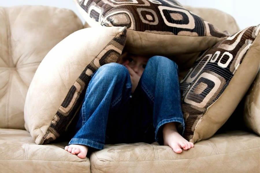 teen in fear hiding on couch
