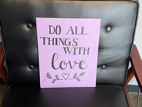An office chair in the head counselor’s office with a slogan that reads, 'Do all things with love.'